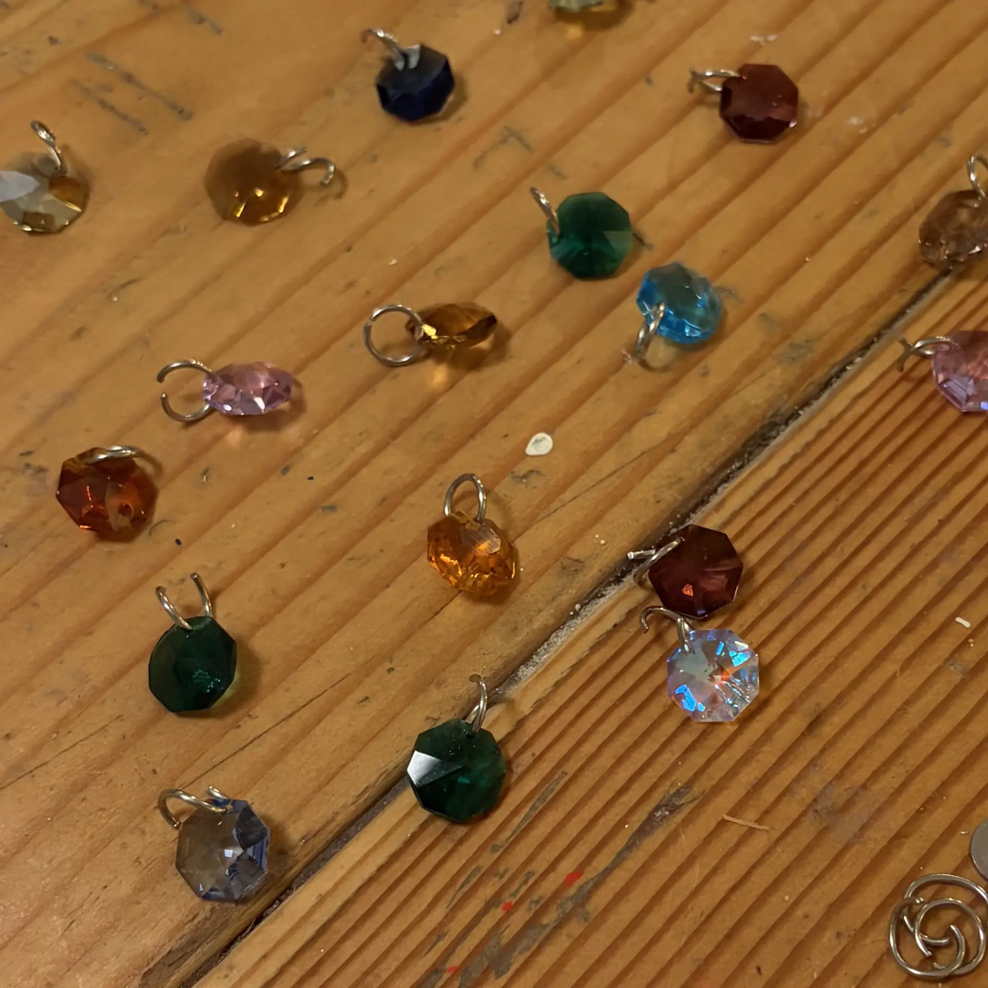 Swarovski crystal octagons in many colors, laid out on the studio workbench.